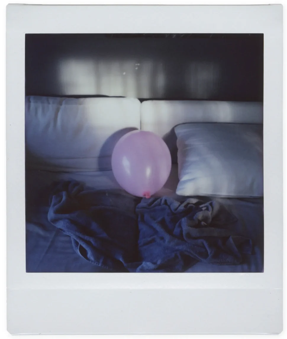 a pink ballon lies forlornly in a bed